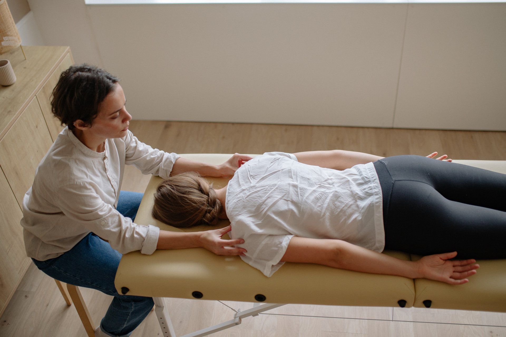 Chiropractor gently examining a patient on an adjusting table