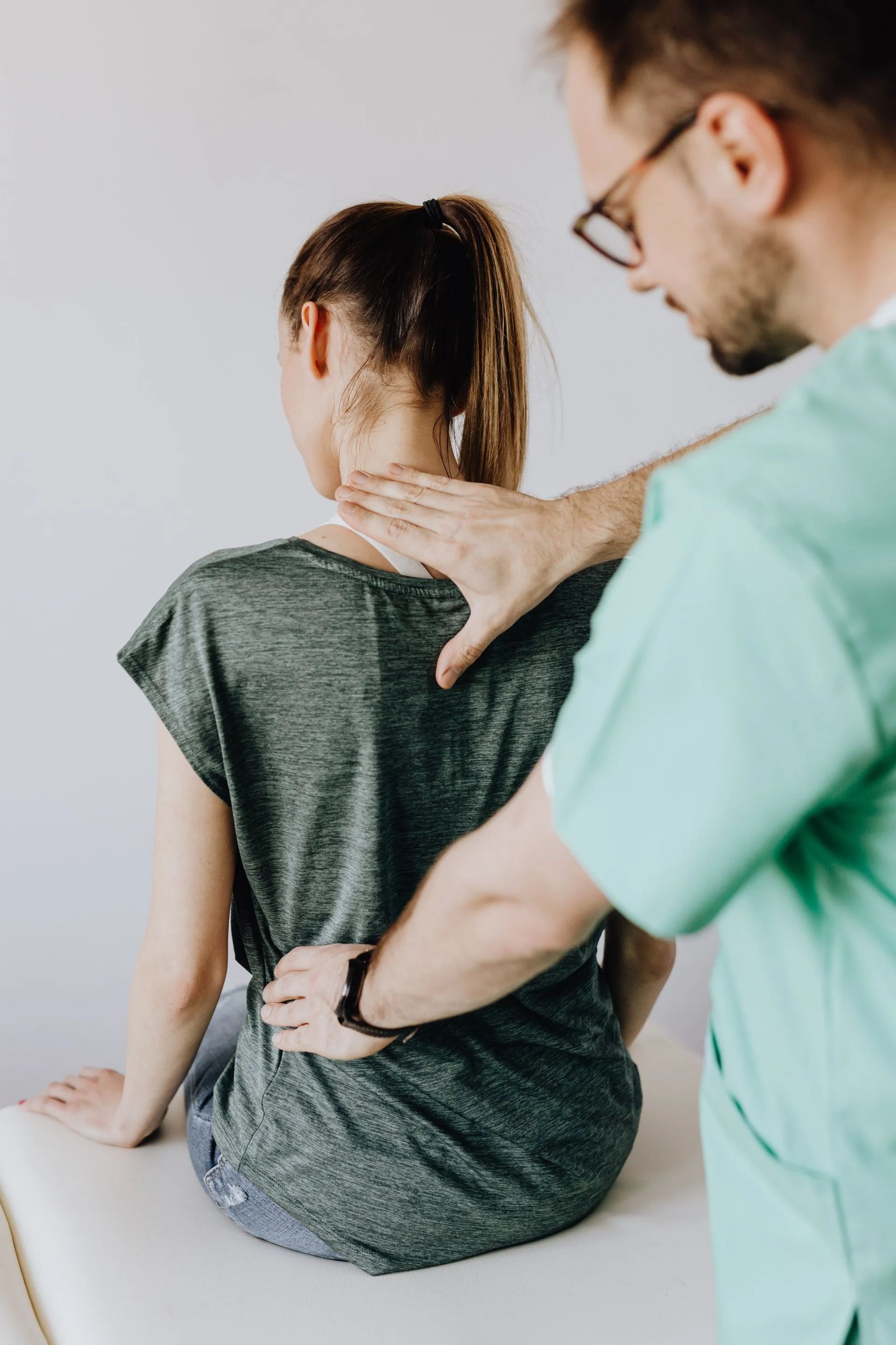 Chiropractor gently examining a patient's back